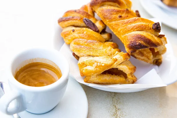 Geleneksel İtalyan kahvaltısı. Küçük beyaz bir fincan sıcak kahve ristreto ve elma ve fındıklı iki taze kruvasan. Günaydın konsepti. Gün ışığı. Ev yapımı fırın. Ginseng sıcak içeceği ve elmalı turta. 