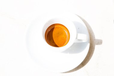 Beyaz yüzeyde yuvarlak beyaz kahve fincanı. Yüksek kontrastlı resim. Aydınlık yaz gününde geleneksel İtalyan ristreto 'su. Üst görünüm geometrik yuvarlak kompozisyon. Küçük bir fincanda sıcak kafein içeceği.. 