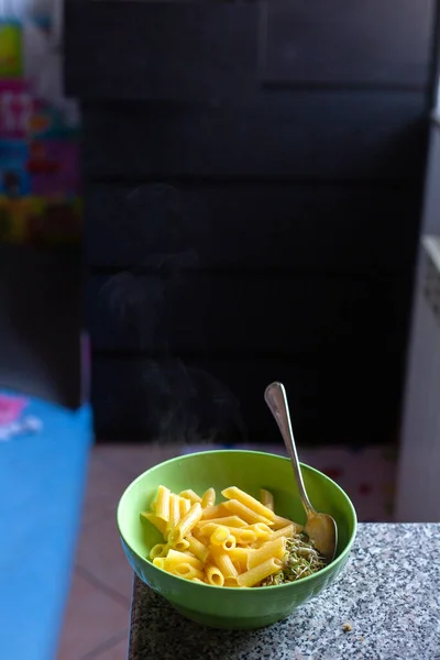 Masada, içi kremalı makarna ve peynirle dolu lezzetli yeşil bir kase var, içinde servis için bir kaşık var.