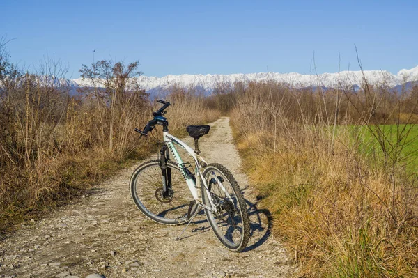 Udine, İtalya (26 Aralık 2020) - Bottecchia MTB motorlu bir toprak döngü yolunun panoramik görünümü ve kuzey İtalya 'daki Alpler' in arka planı