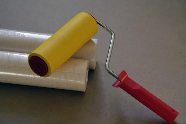 Dos rollos de papel pintado en envoltura y un rodillo — Foto de Stock