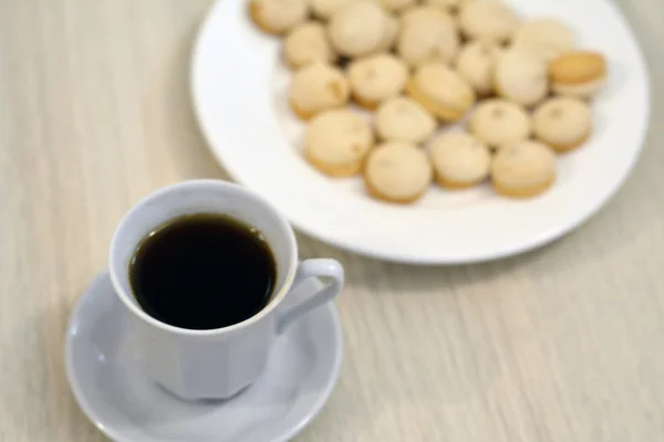 Secangkir kopi hitam dengan sepiring biskuit — Stok Foto