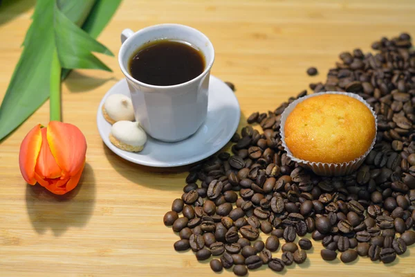 Cupcake no monte de grãos de café e uma xícara de café fresco — Fotografia de Stock