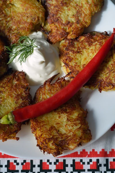 Draniki - thin potato pancakes - on a plate with sour cream — Stock Photo, Image