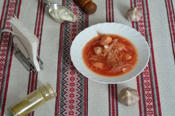 Plate of hot borsch with heads of garlic — Stock Photo, Image