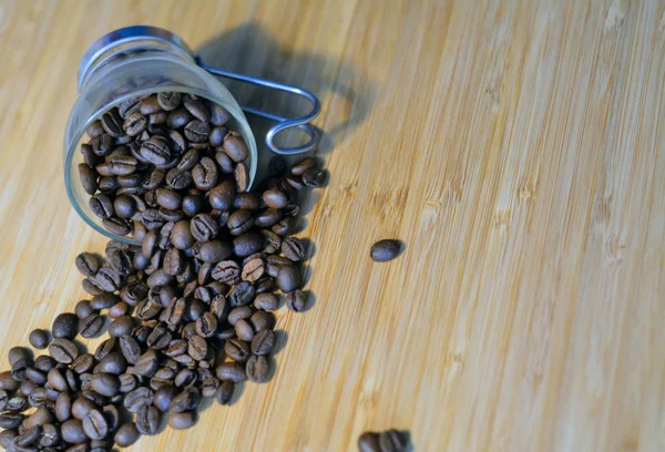 Small glass cup on wooden table with coffee beans — Stock Photo, Image