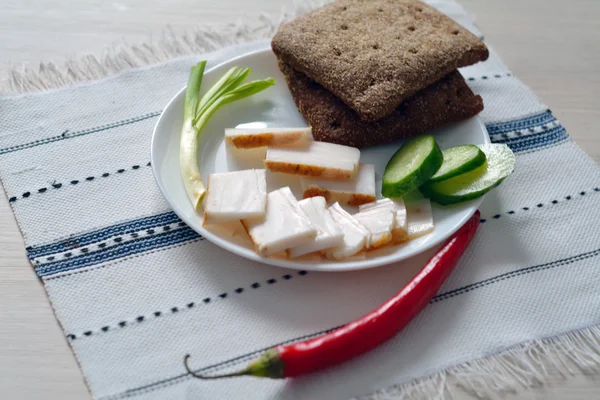 Fresh lard, rye bread, slices of cucumber and onion — Stock Photo, Image