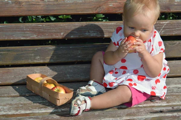 Dziewczynka siedzi na ławce z jabłkami — Zdjęcie stockowe