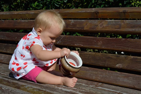 Baby girl examine the pot  on the bench — Stock Photo, Image