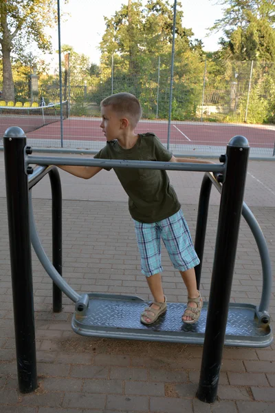 A boy exercising on outdoor equipmnent — Stock Photo, Image