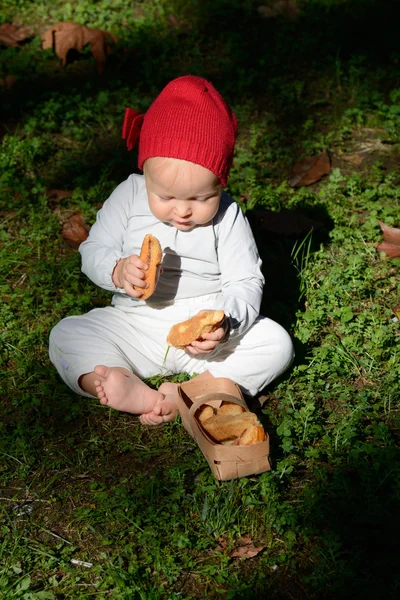 A toddler girl eat two rusks next to the basket — Stock Photo, Image