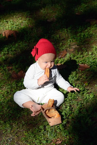 Little red riding hood: a tiny girl sits in the forest — Stock Photo, Image