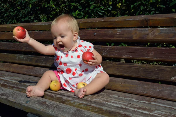 A baby girl throwing apples to the ground — Stock Photo, Image