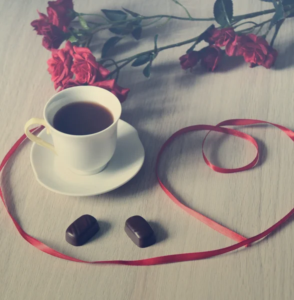Tasse de café noir avec deux bonbons et fleurs — Photo