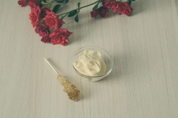 sugar scrub in a glass bowl with a sugar stick and roses