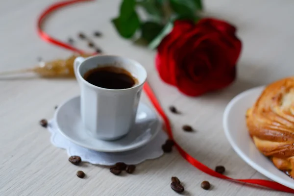 Warme koffie in een kopje, broodje en een suiker stick Stockfoto