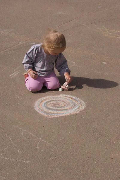 Girl draws a spiral with chalk — Stock Photo, Image