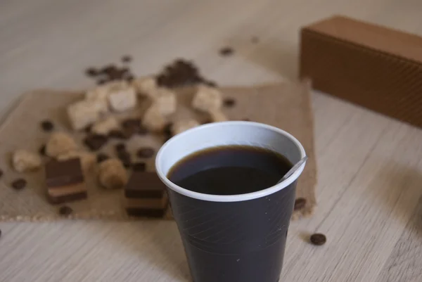 Café em uma xícara de plástico com doces e grãos de café — Fotografia de Stock