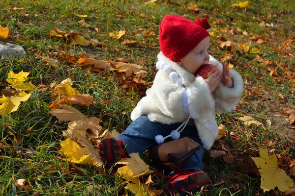 Dziewczyna siedzi w jesiennych liści z jabłkiem — Zdjęcie stockowe