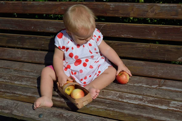 A girl plays with apples on the bench — Stock Photo, Image