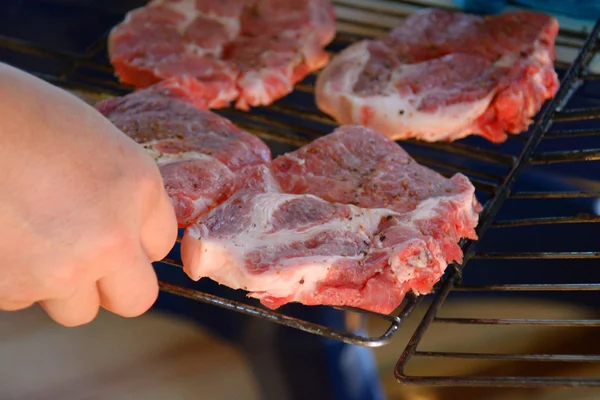 Die Hand des Mannes legt die Steaks auf den Grill — Stockfoto