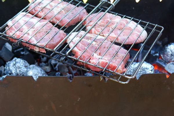 Čtyři syrové steaky na grilu, vaření — Stock fotografie