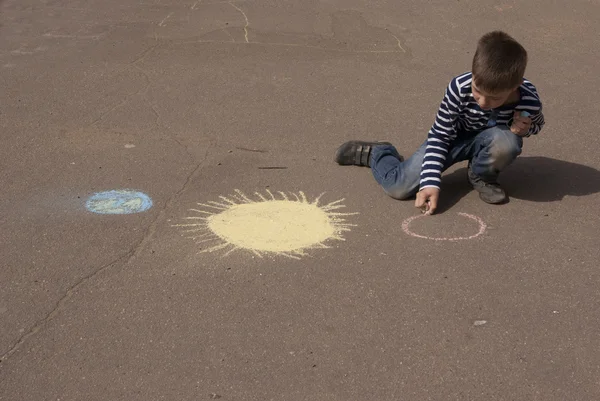 Jongen tekening zon en planeten met gekleurde krijtjes Rechtenvrije Stockafbeeldingen