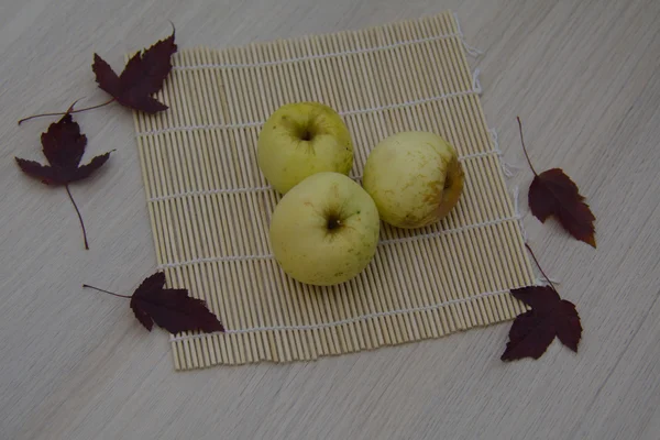 Três maçãs no tapete de palha — Fotografia de Stock
