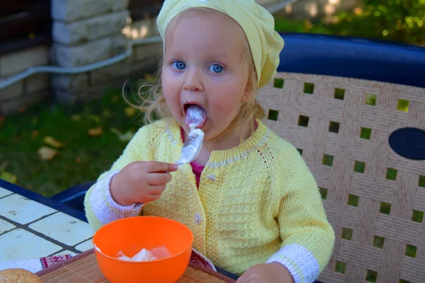 Toddler girl eats sour cream with a spoon — Stock Photo, Image