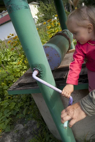 Old iron well and a girl watching — Stock Photo, Image