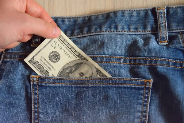 Рука берет стодолларовую банкноту из кармана джинсов — стоковое фото