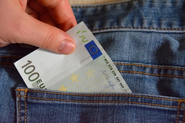 Mano con un billete de 100 euros. ponerlo en el bolsillo de los vaqueros — Foto de Stock