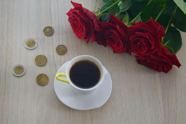 Moedas espalhadas sobre a mesa, com café e rosas — Fotografia de Stock