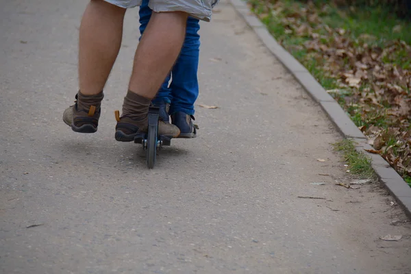 Legs of two people on one scooter — Stock Photo, Image