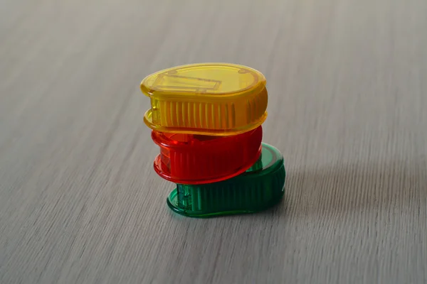 Bright plastic sharpeners on the wooden table, in a pile — Stock Photo, Image