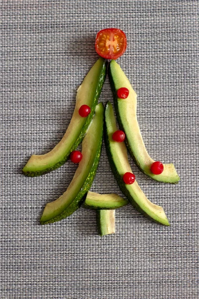 New year meal. Avocado shaped as Christmas tree with tomato on top. Healthy organic food for festive table