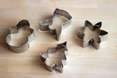 Yılbaşı kurabiyeleri için hamur kesmek için metal formlar masanın üzerinde yatıyor.