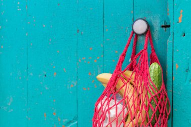 Ön kapıda ipli alışveriş torbası asılı. Kapıdaki yemek paketinde kendini izole etmek için.