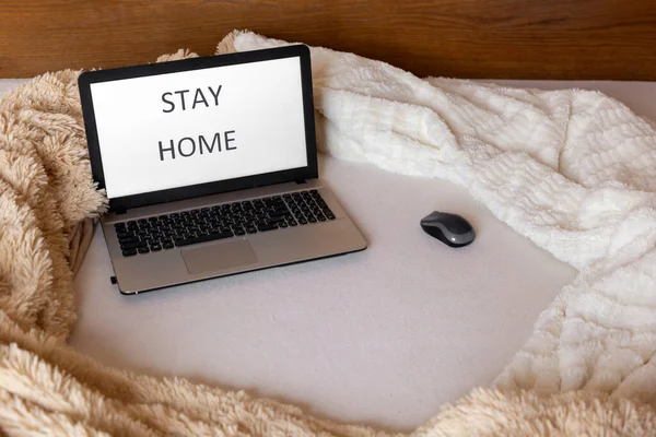 画面に 家にいる と書かれたベッドの上のノートパソコン 居心地の良いホームコンセプト 家からの仕事 — ストック写真