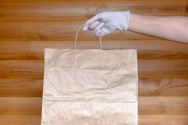 Ręce Białych Rękawiczkach Medycznych Trzymają Papierową Torbę Przesyłką Domu — Zdjęcie stockowe