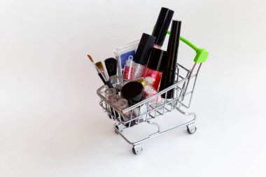 Makyaj malzemeleriyle alışveriş arabası: dekoratif gölgeler, fırçalar, ruj.