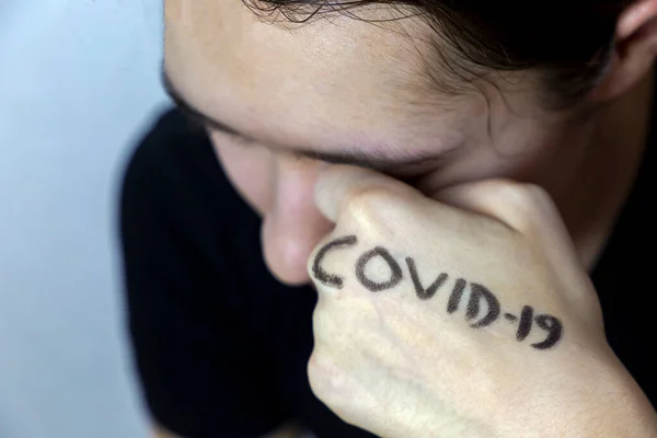Girl rubbing eyes with hands with covid-19 written on it. Stop spreading virus. Don\'t touch eyes with dirty hands