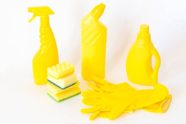 Sarı temizlik seti. Beyaz arka planda şişeler, süngerler, lastik eldivenler 