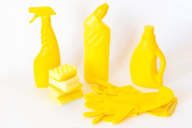 Sarı temizlik seti. Beyaz arka planda şişeler, süngerler, lastik eldivenler 