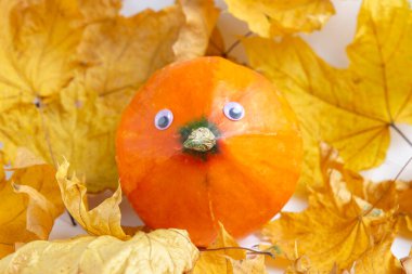 Sonbahar yaprakları arasında mantar şeklinde gözleri ve yüzü olan balkabağı. Şükran Günü ve Cadılar Bayramı konsepti. Vejetaryen menüsü