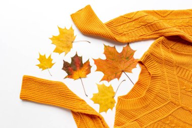 Renkli sarı ve kırmızı yapraklı, turuncu uzun kollu örgü süveter. Sonbahar renkli giysiler düz yatıyordu