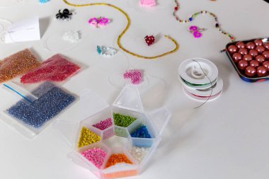 Yaratıcı, parlak ve renkli boncuklar beyaz masada. El sanatları işyeri. Güzel diy mücevher ve rahatlatıcı stres rahatlatıcı hobi ve aktivite
