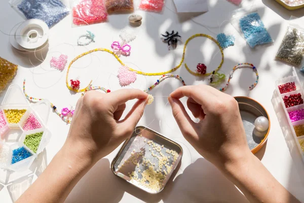 Beading workplace with hands in the process of handicraft. Beautiful diy jewelry and calming stress releasing hobby and activity