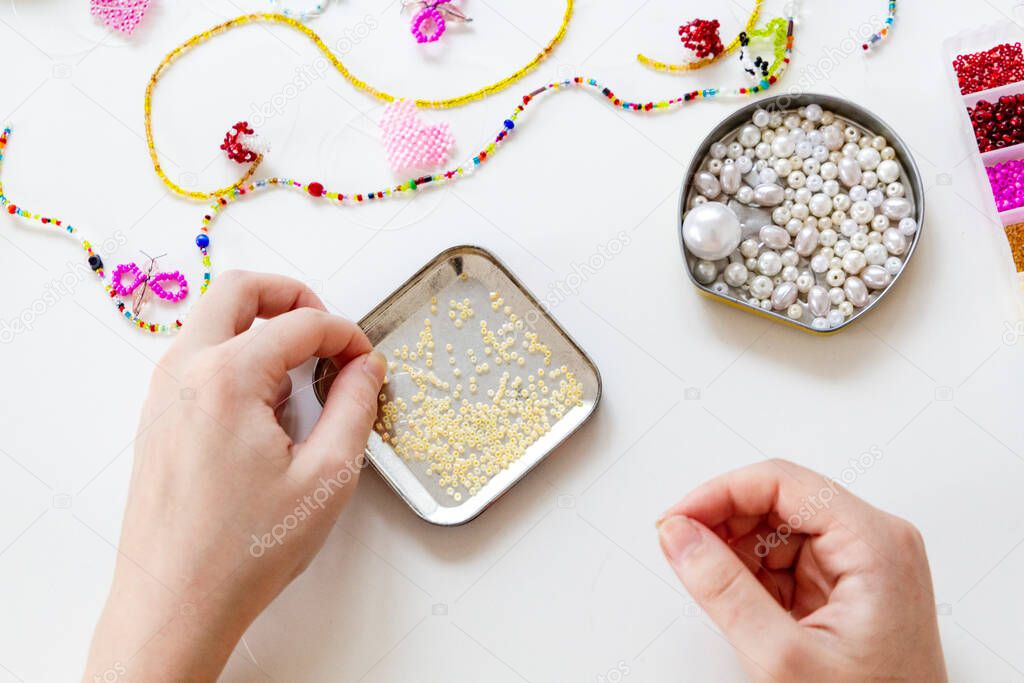 Beading workplace with hands in the process of handicraft. Beautiful diy jewelry and calming stress releasing hobby and activity