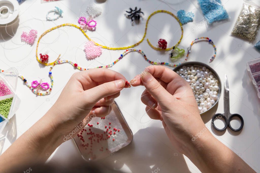 Beading workplace with hands in the process of handicraft. Beautiful diy jewelry and calming stress releasing hobby and activity